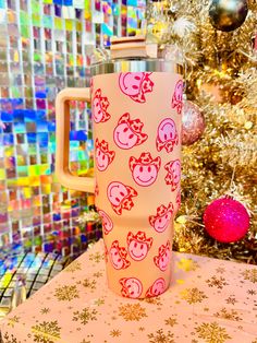 a pink cup sitting on top of a table next to a christmas ornament