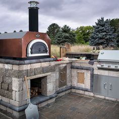 an outdoor pizza oven built into the side of a stone wall with grill and cooking utensils