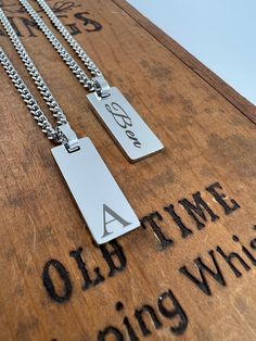 two necklaces that are sitting on top of a wooden box with words written on it