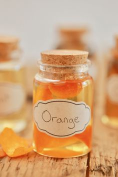 a jar filled with orange peels sitting on top of a wooden table next to other jars