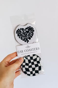 someone is holding up two badges in their hand, one with the word car coasters on it