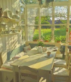 a table and chairs in front of a window with potted plants on the windowsill