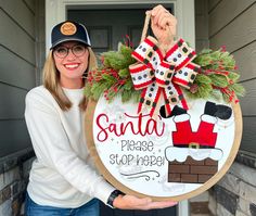 a woman holding up a sign that says santa please stop here