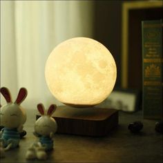 two little rabbits sitting next to a lamp on a wooden stand with the moon in the background