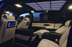 the interior of a luxury car with white and black leather seats, windows, and lights