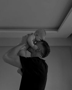 a man holding a baby up to his face while he holds it in the air