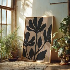 a framed art piece sitting on top of a rug next to potted plants