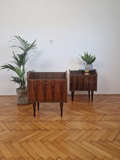 two planters sitting on top of wooden tables in a room with hard wood flooring