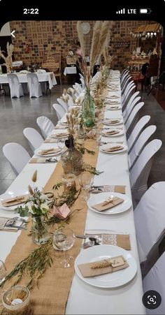 a long table set with place settings and flowers on it for an elegant dinner party