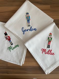 three personalized embroidered napkins on top of a wooden table