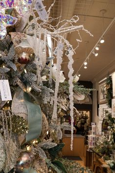 a decorated christmas tree in a store with ribbons and ornaments hanging from the ceiling,