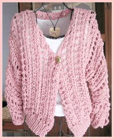 a pink knitted cardigan is hanging on a rack