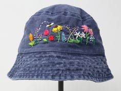 a blue hat with embroidered flowers on it