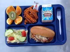 a blue tray topped with a sandwich and veggies