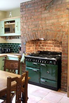 a kitchen with an oven, table and chairs next to a brick wall in the background