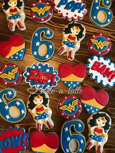 decorated cookies with the number six and wonder woman on them are displayed in front of a wooden table