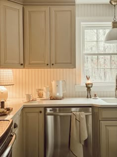 a kitchen with beige cabinets and white counter tops, an open dishwasher in the middle