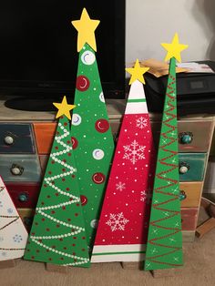 three wooden christmas trees sitting in front of a tv