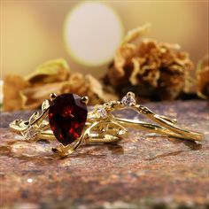 two gold rings with garnetia and diamond accents on top of a marble surface