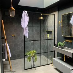 a bathroom with black and white tiles, gold accents and a plant in the corner