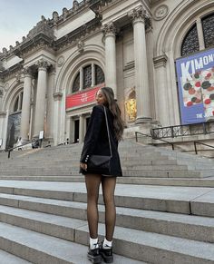 a woman is standing on some steps in front of a building