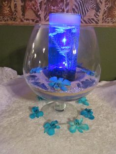 a glass bowl filled with water and blue flowers