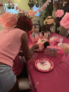 a woman sitting at a table with pink decorations