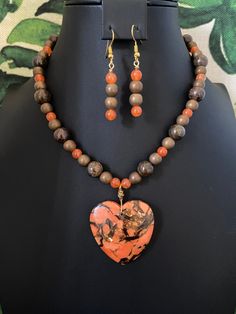 You will receive a gorgeous, orange, heart-shaped bornite pendant and beaded necklace with matching earrings.   Bornite is a mineral with metallic inclusions.  This pendant has wonderful golden and bronze inclusions.  To highlight this beautiful heart pendant, I have used orange jade, bronzite, and metallic bronze spacer beads.   I am cuckoo in general, but I'm especially crazy about heart pendants!!  I'm also a fanatic about color-matching and believe I have out-done myself choosing beads that Orange Heart Beads Jewelry For Gift, Orange Jewelry With Heart Beads For Gifts, Orange Heart Beads For Jewelry Making, Handmade Orange Heart Jewelry, Brown Heart Shaped Jewelry With Heart Beads, Multicolor Heart Beads Pendant Necklace, Handmade Heart-shaped Orange Jewelry, Orange Heart Charm Jewelry, Handmade Orange Heart-shaped Jewelry