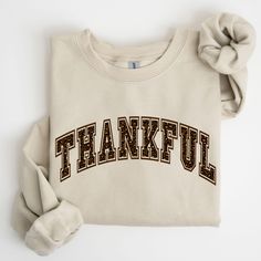 Celebrate the season of gratitude in style with our Thankful Sweatshirt! This cute and cozy sweatshirt is perfect for Thanksgiving gatherings, fall outings, or just embracing the warmth of autumn. Featuring a simple yet stylish "Thankful" design, it's a great addition to your fall wardrobe or a thoughtful gift for loved ones. Whether you're sharing a meal with family or reflecting on the things you're grateful for, this sweatshirt will keep you feeling warm and festive. ✨ This shirt features a h Casual Fleece T-shirt For Fall, Fleece T-shirt With Letter Print For Fall, Cotton Sweatshirt With Text Print For Fall, Long Sleeve Fleece T-shirt For Fall, Fall Cotton Sweatshirt With Lettering, Fall College Sweatshirt With Text Print, Fall Letter Print T-shirt For Loungewear, College Fall Sweatshirt With Text Print, Cotton Sweatshirt With Lettering For Fall