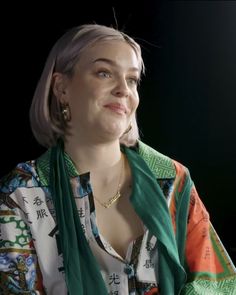 a woman with grey hair wearing a green scarf and gold earrings on her left ear