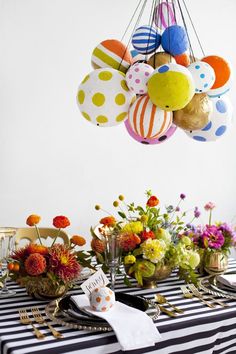 the table is set with colorful flowers and balloons hanging from the chandelier above it