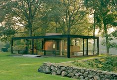 a glass house sitting in the middle of a lush green field next to some trees