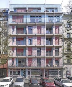 an apartment building with multiple balconies and cars parked on the street in front