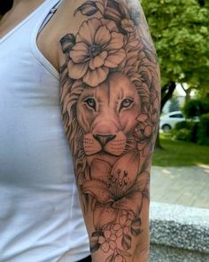 a woman's arm with a lion and flowers tattoo on the left side of her arm