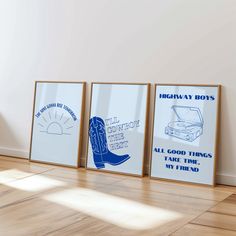 three framed posters on the wall in an empty room with hard wood flooring and white walls