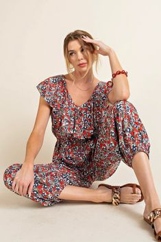 A comfortable jumpsuit with a pop of red and sprinkle of flowers. This jogger style jumpsuit has an elastic waistline, shaping the loose, lightweight fabric. There is a ruffled fabric detail along the neckline and sleeves, and side pockets. Style with sandals for a picnic in the park. Model is 5'10" and wearing her true size Small. Small: Bust 18", Length 54.5" 100% Rayon Ruffled Fabric, Jumpsuit With Pockets, Style Jumpsuit, Pop Of Red, Picnic In The Park, A Picnic, Floral Jumpsuit, Fashion Joggers, Denim Jumpsuit