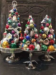 three silver trays with christmas trees on top of eachother, one decorated in different colors