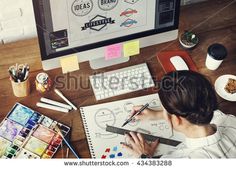 a person sitting at a desk with a computer and some paintbrushes on it