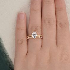 a woman's hand with a diamond ring on top of her finger and the other hand holding an engagement ring