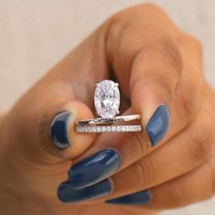 a woman's hand holding a ring with a diamond on it and blue nail polish