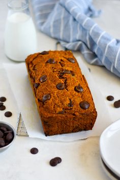 a loaf of chocolate chip bread sitting on top of a table next to a glass of milk