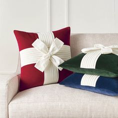 two pillows with bows on them sit on a couch in front of a white wall