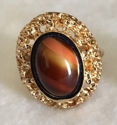 Beautiful vintage Karatclad and polished stone ring from our 1980's collection that are new, never worn and in excellent condition. The ring measures 7/8" long x 3/4" wide with the stone measuring 15x10mm.  The colors vary with each piece but are each a shade of brown from light to dark. Tigers Eye Ring, Eye Ring, Tigers Eye, Ring Vintage, Stone Ring, Tiger Eye, Stone Rings, Tigers, Vintage Rings