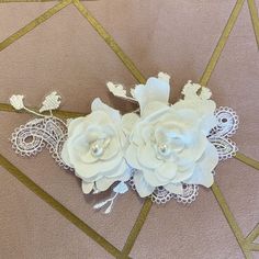 two white flowers are sitting on top of a piece of fabric with gold trimmings