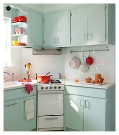 a white stove top oven sitting inside of a kitchen next to a sink and cabinets