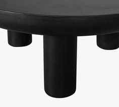 a black table with three legs and two round bases on each side, against a white background