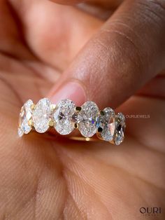 a woman's hand holding a five stone diamond ring