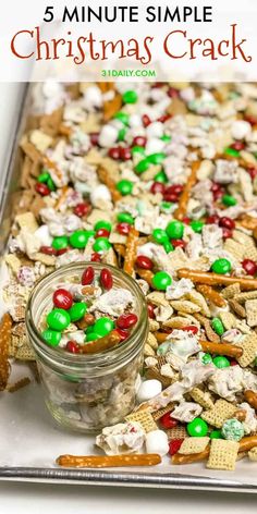 christmas cracker mix in a glass jar on top of a cookie sheet with pretzels and candy