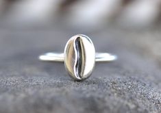 This listing is for one adorable and elegant sterling silver coffee bean ring!  It is pure sterling silver and looks like a real coffee bean!  Wear it solo or stack with other bands for a bohemian look.  They make a great gift for coffee lovers and baristas! These adorable beans are forged from raw sterling silver ingots forged using a steel die and then fired onto sterling silver 14 gauge round wire.  - Choose your size at checkout! - Coffee bean measures 12mm by 8mm. - Ring band is 1 mm thick. Kawaii Ring, Coffee Ring, Coffee Jewelry, Barista Gift, Silver Ingot, Cute Ring, Real Coffee, Silver Rings Simple, Jewelry Cute