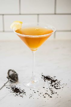 a glass filled with liquid next to a scoop of black pepper and a lemon slice